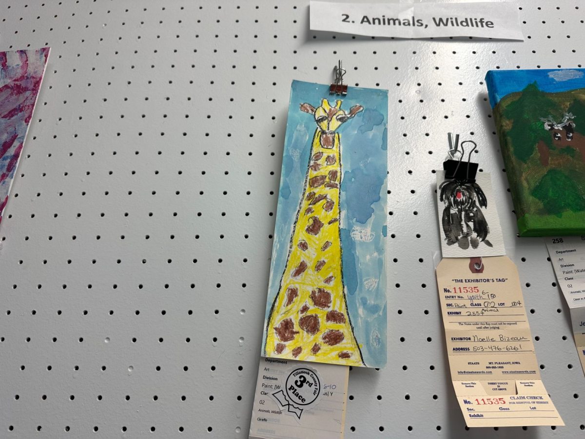 Giraffe drawing on blue background clipped to a pegboard with exhibit tags nearby, part of an Animals, Wildlife display label above.